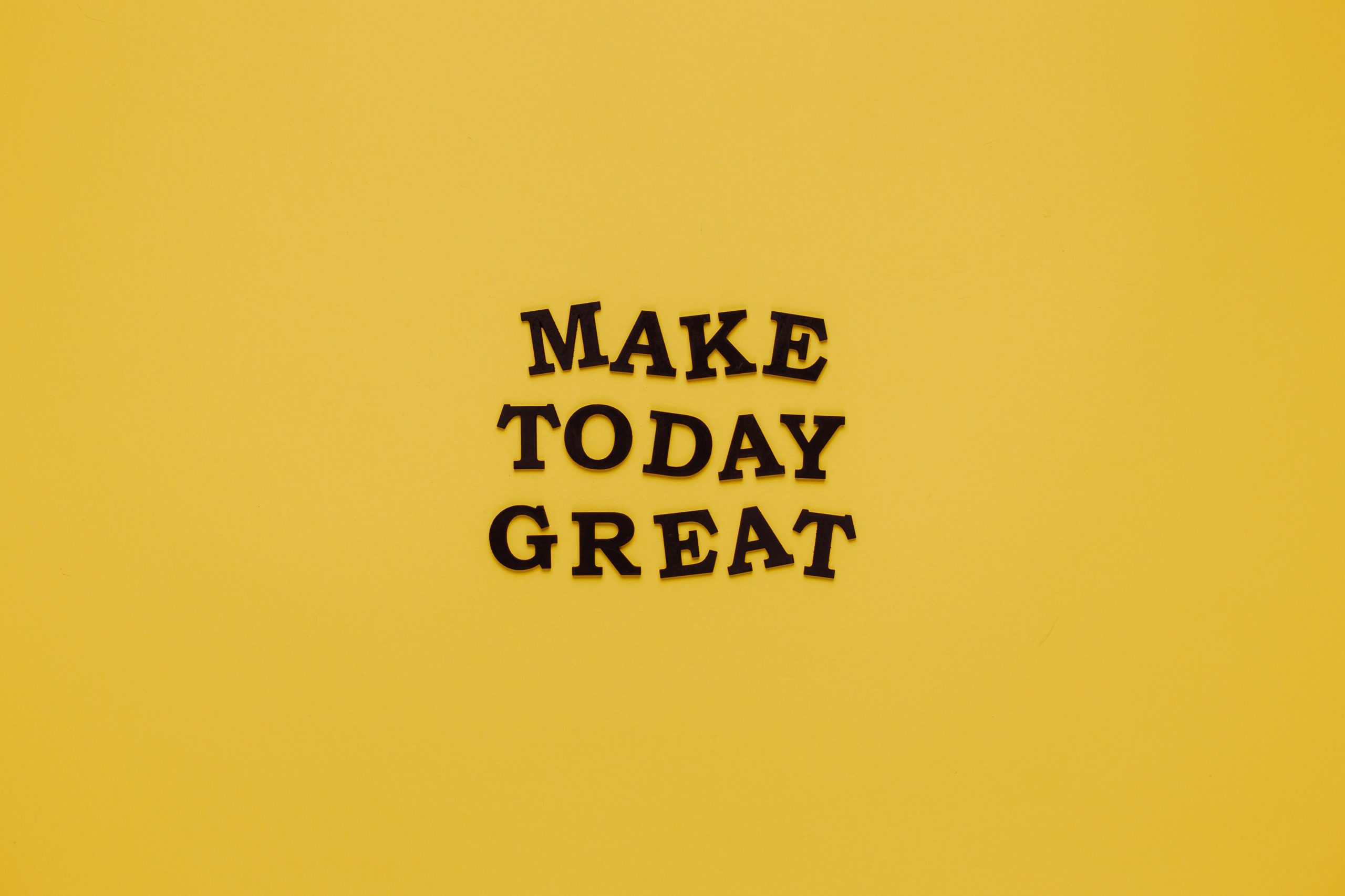Simple and motivational quote 'Make Today Great' on a minimalist yellow background for inspiration.